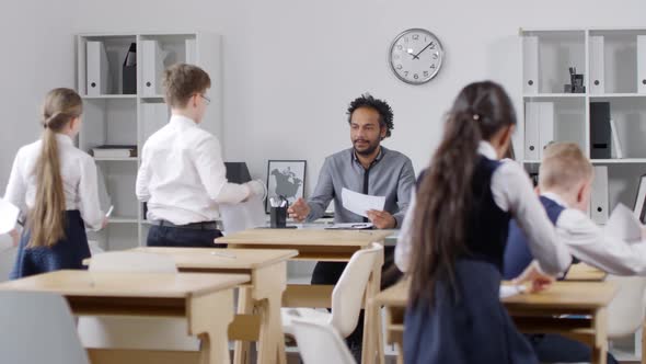 Primary School Pupils Submitting Answer Sheets to Black Teacher alt