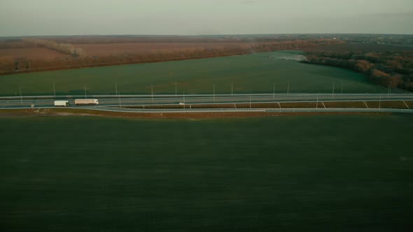 Aerial Shot of a Trucks and Cars on the Road Out of Town on the Highway on Sunset alt