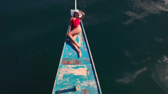 Drone Above Sea With Woman Sunbathing On Outrigger Boat alt