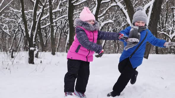 Children Play in the Winter in the Forest a Girl Pushes a Boy Into a Snowdrift