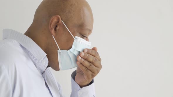 Old elderly black business man. Sick African American person wearing a face mask coughing alt
