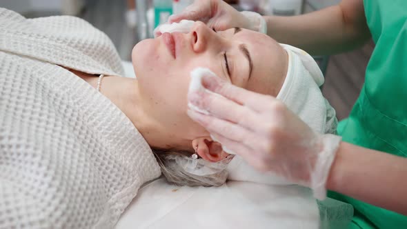 Female Beautician Makes Face Rejuvenation and Cleansing Procedure for Girl alt
