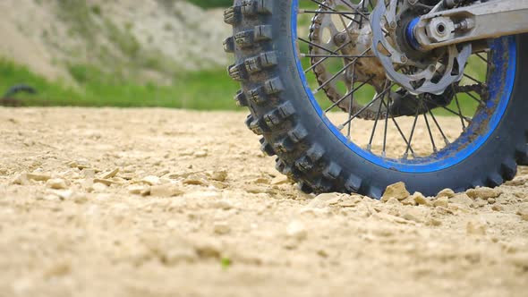 Close Up Wheel of Powerful Off-road Motorcycle Spinning and Kicking Up Dry Ground or Dust alt