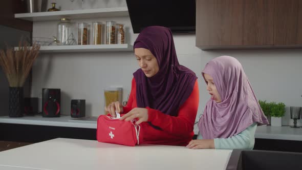 Worried Lovely Muslim Mom Looking for Medicine in First Aid Kit to Coughing Sick Little Daughter alt
