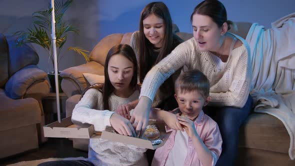 Big Family Eating Pizza and Taking Slices From Box While Watching TV Show or Movie in Living Room alt