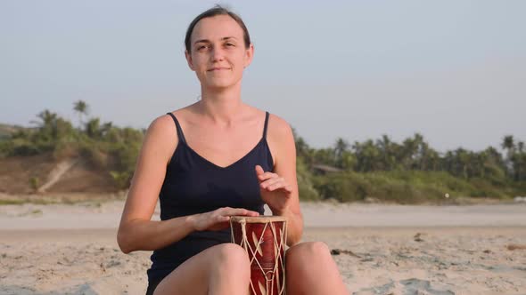 Young Cheerful Woman Playing Drums on Sandy Beach in Slow Motion