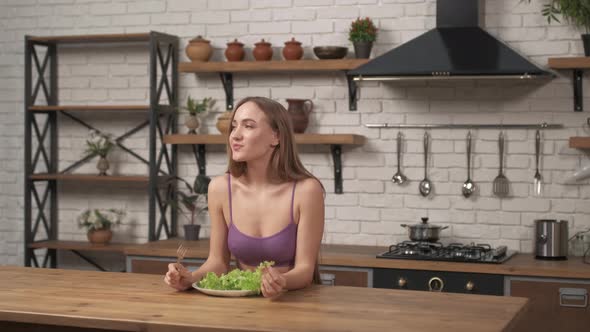 Woman siting at a table on the home kitchen. Sporty girl eating cabbage leaves adheres to a diet alt