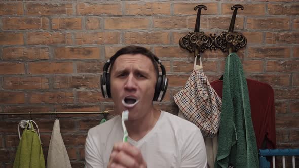 A Man Brushes His Teeth and Dances To the Music Playing in His Headphones.