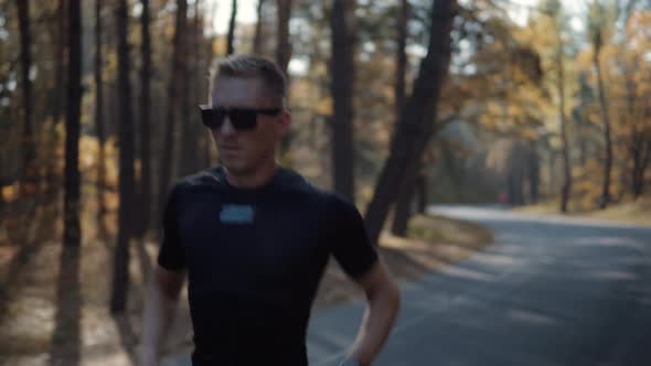 Running Man In Forest At Sunset. Runner Man Fit Athlete Legs Jogging On Trail Ready Triathlon. alt
