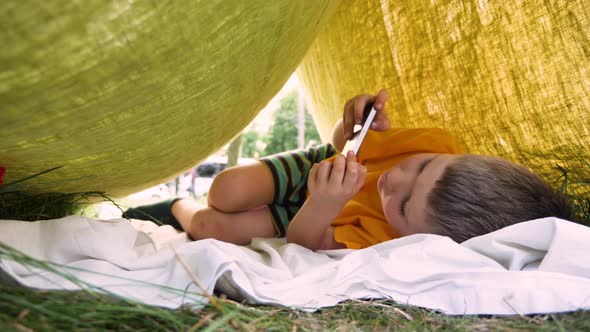 Trekking Little House for Children. Kid with Phone, Mobile Playing Video Game. Boy Spending Summer