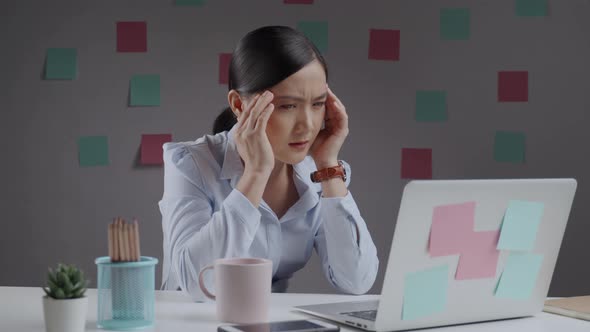 Asian woman working on a laptop has headache sitting