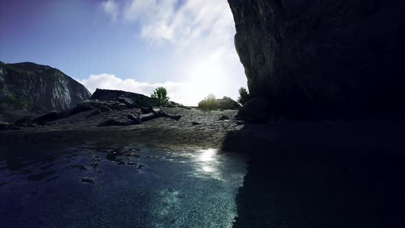 Sandy Beach in Bay Surrounded By Steep Mountains in Sunset alt