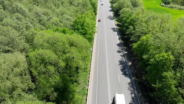 The Road with Cars. The Highway Goes Through Fields and Forests with Passing Cars.