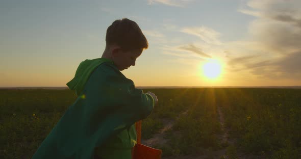 A Boy Is Standing on the Field and Repairing Plane. Sunset.  alt