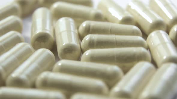 Many Beige Pills Are Rotating on White Background Closeup View