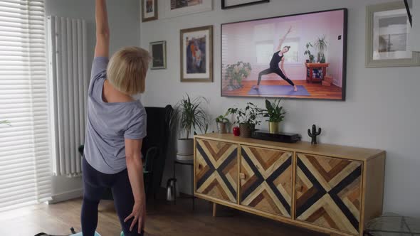 Video of active senior woman exercising in front of TV. Shot with RED helium camera in 8K. alt