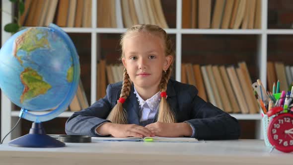 young hispanic schoolgirl primary school student sitting at her desk