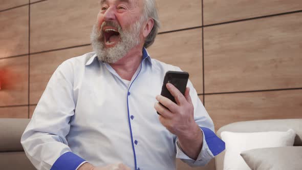happy bearded grandfather winner celebrate victory success read good news in cell text message. Over alt
