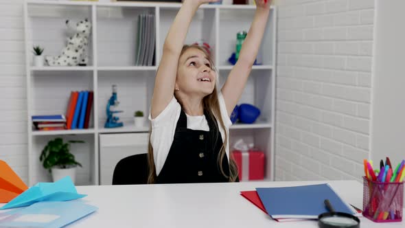 Happy Schoolgirl Having Fun Playing with Paper Plane at School Lesson in Classroom Happiness