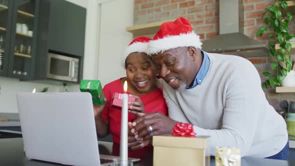 Happy african american senior couple in santa hats on video call on laptop at christmas time alt