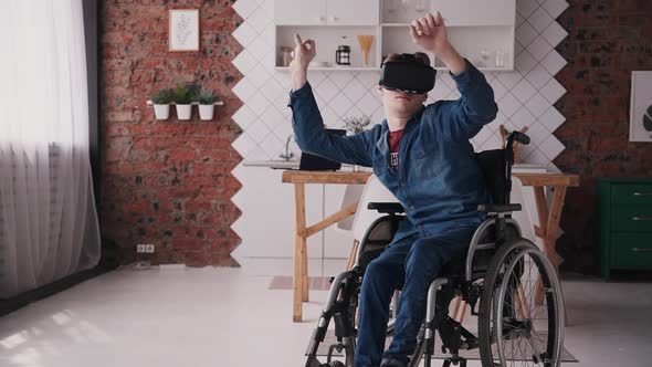 Portrait Young Disabled Man in a Wheelchair at Home, Uses 3d Technology, Vr Helmet.