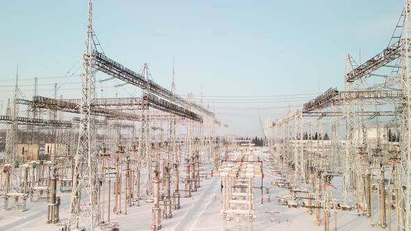 Aerial View of an Electrical Substation in Winter with High Pylons and Voltage Distribution Cables