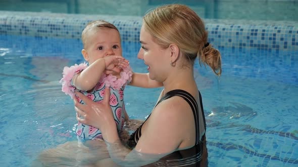 Young Cheerful Mother and Little Daughter Enjoying Swimming in a Swimming Pool alt