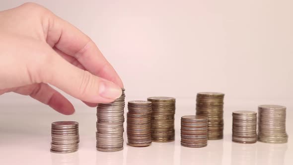 A woman's hand puts coins in a column. Investment concept. Metallic currency