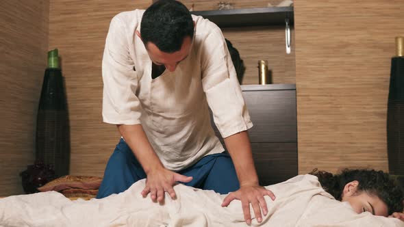 Male Thai Massagist is Treating Young Woman's Back alt