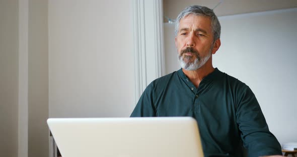 Man using laptop while having breakfast in living room 4k alt