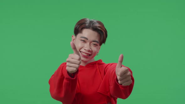 Happy Asian Transgender Male Showing Thumbs Up Gesture While Standing In The Green Screen Studio alt