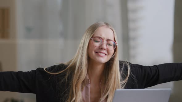 Caucasian Business Woman Girl Blonde in Glasses Sits at Table Looking Into Laptop Opens Mouth Shock alt