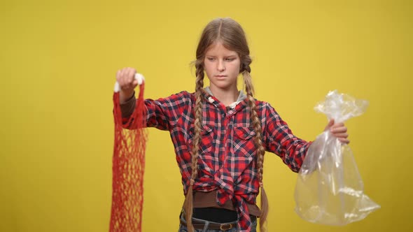 Doubtful Unsure Teenage Girl at Yellow Background with Plastic Bag and Eco Bag alt