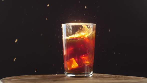 Cola glass with ice cube splash in slow motion