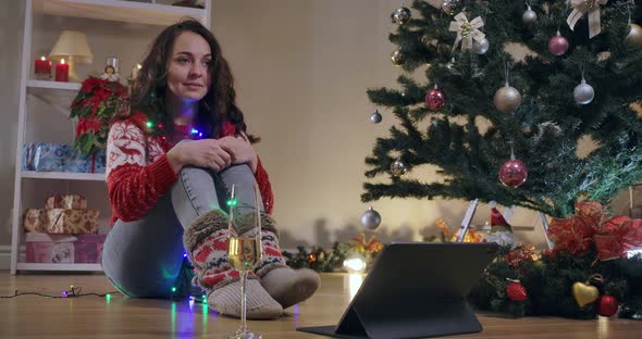 Slim Joyful Young Woman Sitting at New Year Tree with Christmas Lights Waiting Miracle alt