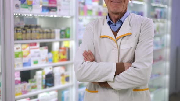 Unrecognizable Senior Male Pharmacist Crossing Hands Smiling Standing in Drugstore alt