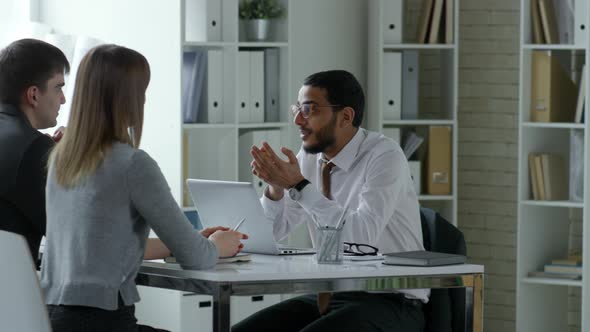 Middle Eastern Businessman Speaking with Coworkers in Office alt