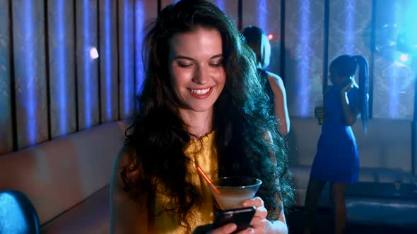 Smiling woman with cocktail drink typing a message alt
