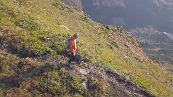 Tourist Hiker with a Backpack Running on Mountain Path in Carpathian Mountains alt