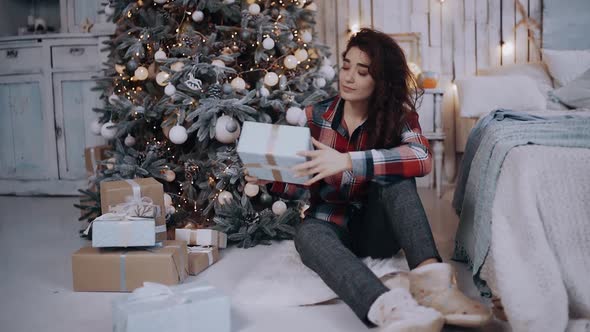 The Chalky Young Woman Took a Present From Under the Tree, Waved It and Smiled Happily alt