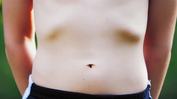 Boy's stomach breathing. Close-up of teenager's body in shorts isolated on green background alt