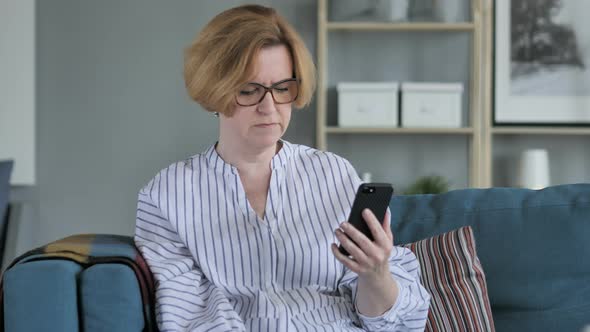 Old Woman Upset for Loss while Using Smartphone alt