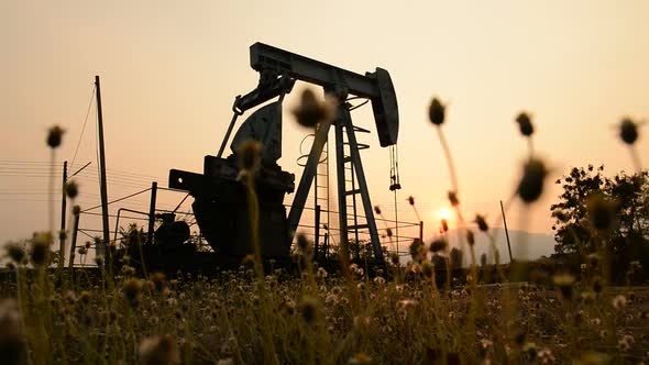 pumpjack at an oil drilling site and sunset