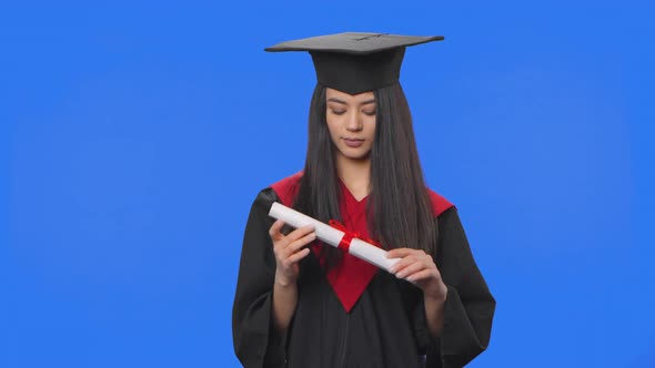 Portrait of Female Student in Cap and Gown Graduation Costume Holding Diploma and Then Throwing It alt