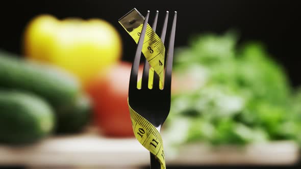 Yellow Measuring Tape on the Fork and Fresh Vegetables on a Wooden Cutting Board alt