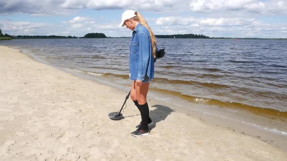 Woman With Metal Detector On City Beach