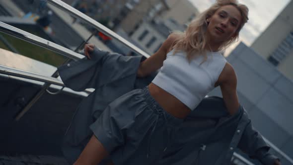 City Woman Moving Body in Parking Lot or Urban Building at Dusk alt
