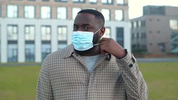 Smiling AfricanAmerican Man Putting Protective Medical Mask Off alt