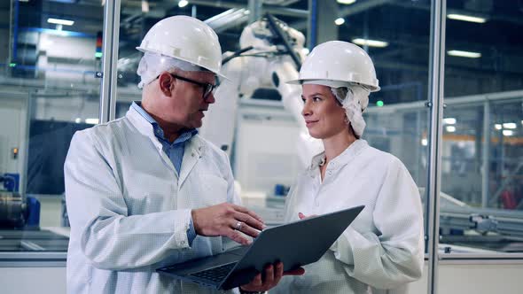 Two Plant Engineers are Talking Near Robotic Machines at Work alt