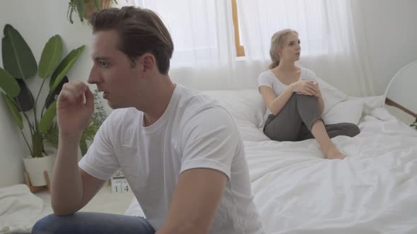Unhappy couple having argument sitting apart on the bed